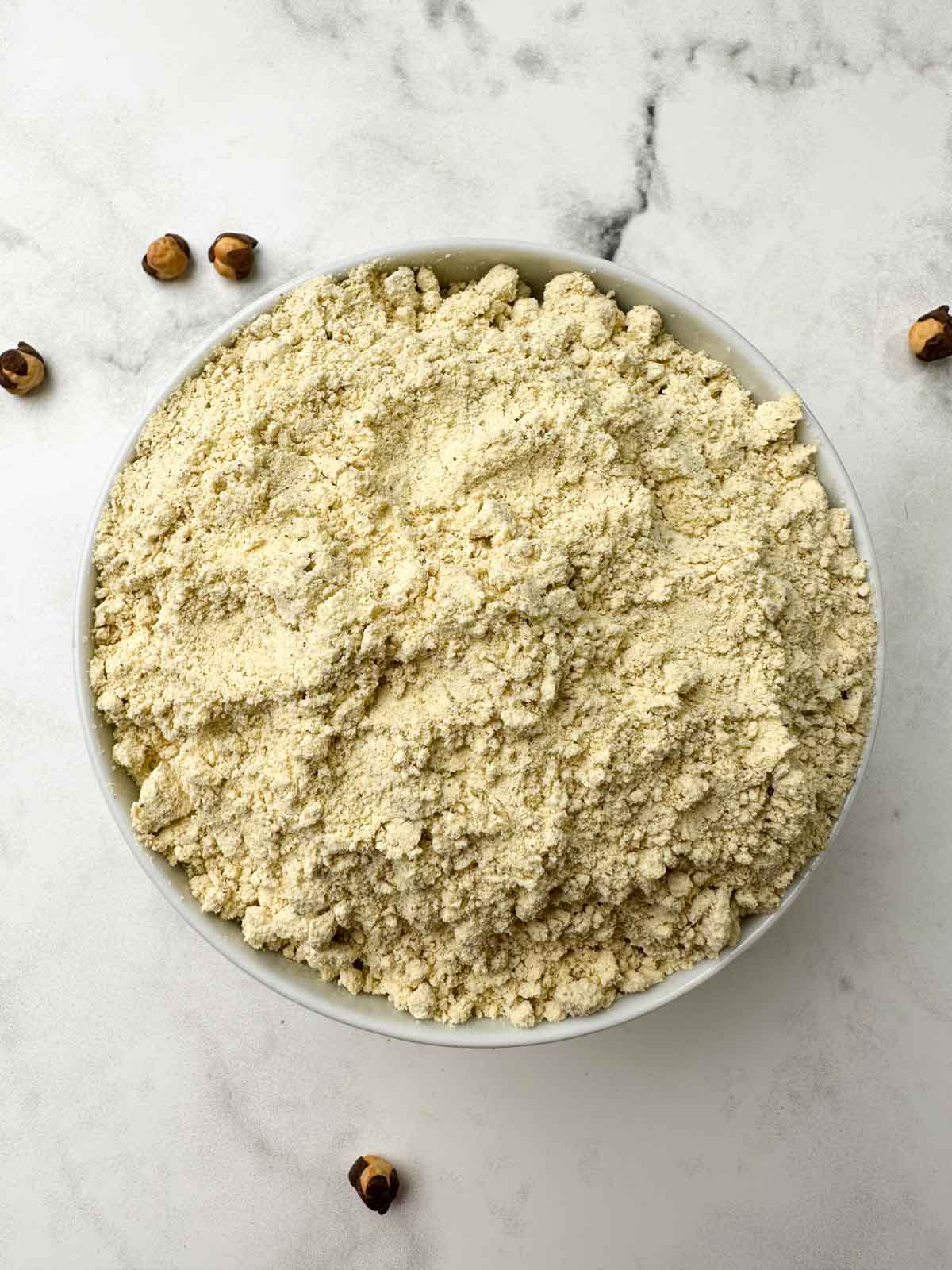 sattu flour in a white bowl with roasted chickpeas on the side