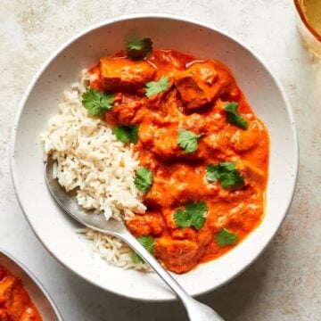 vegan tofu tikka masala served in a bowl with cooked rice and spoon