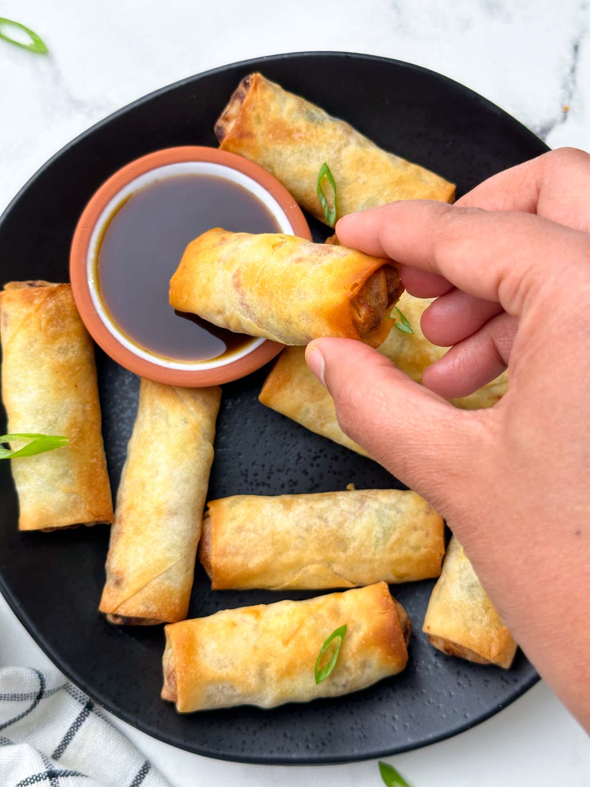 spring roll being dipped in a sauce
