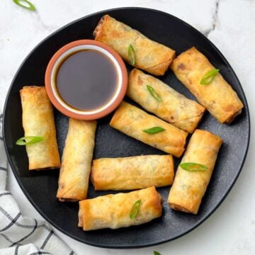 air fryer spring rolls served on the plate with soy ginger sauce garnished with green spring onions
