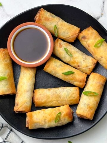 air fryer spring rolls served on the plate with soy ginger sauce garnished with green spring onions