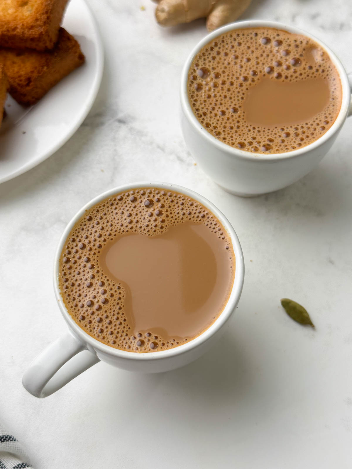 adrak wali chai served in a cup with rusk and ginger knob on the side
