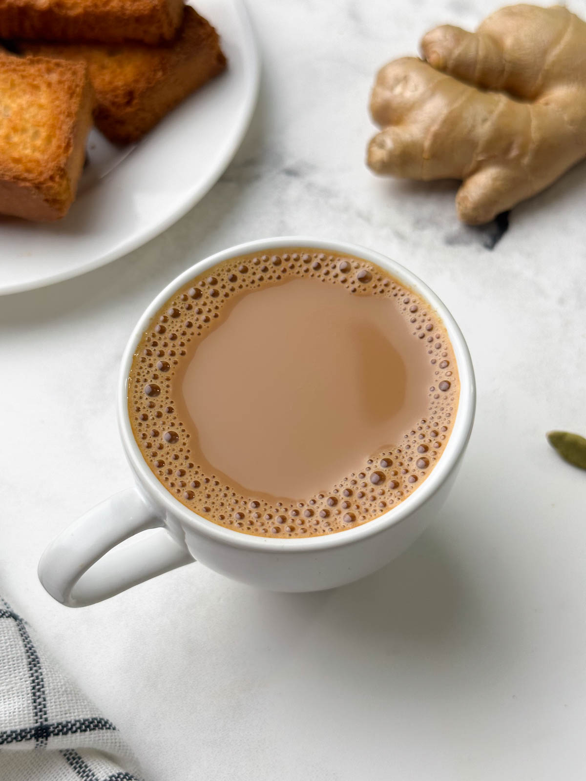 ginger tea served in a cup with rusk and ginger knob on the side