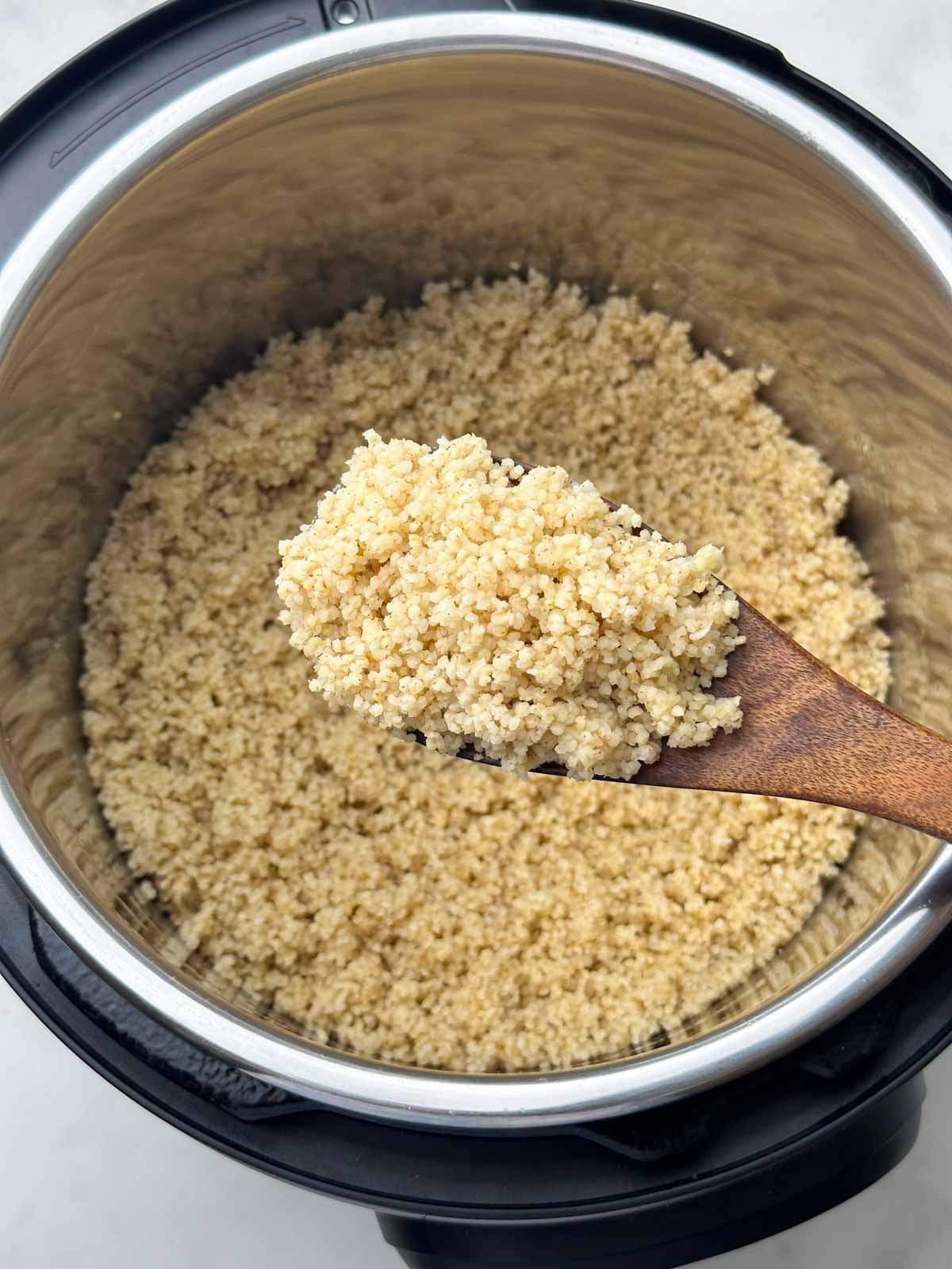 cooked foxtail millet in a ladle and instant pot 