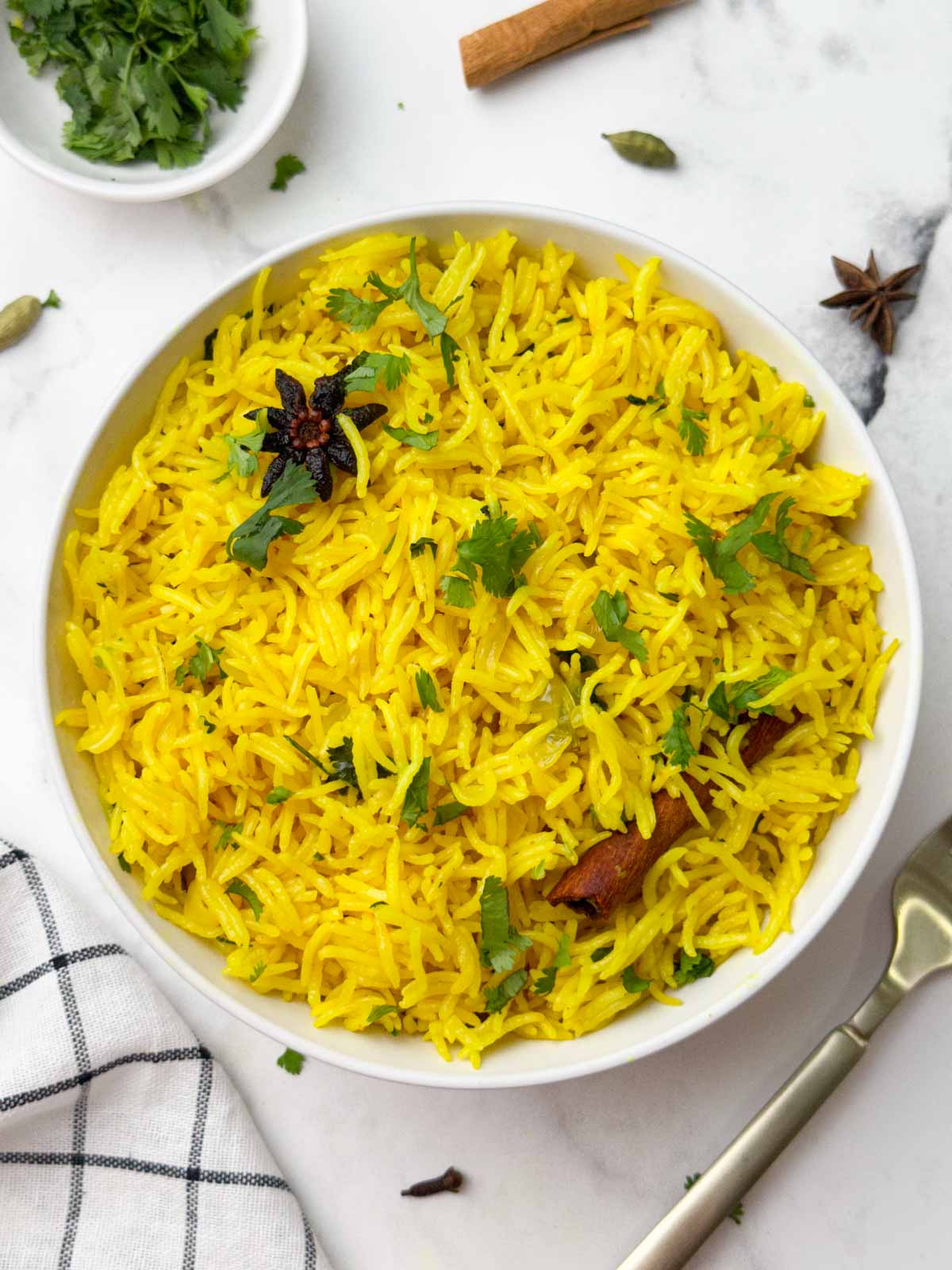 indian turmeric yellow rice served in a bowl with coriander leaves on the side