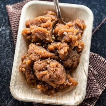 Atta halwa served in a wooden plate with a spoon