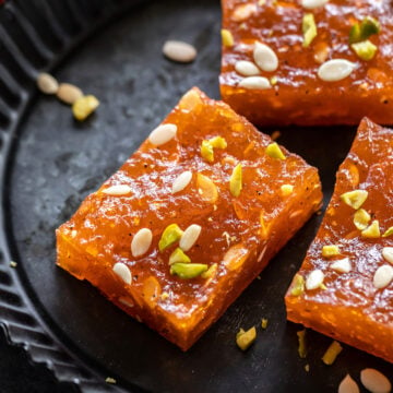Karachi Halwa (Bombay Halwa) pieces on a plate garnished with nuts and melon seeds
