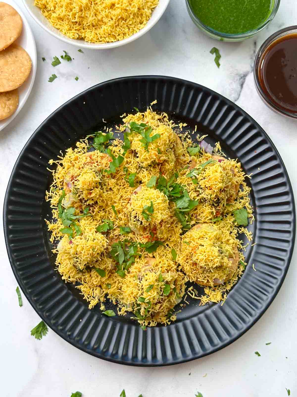 sev puri chaat served on a plate with sev and chutneys on the side