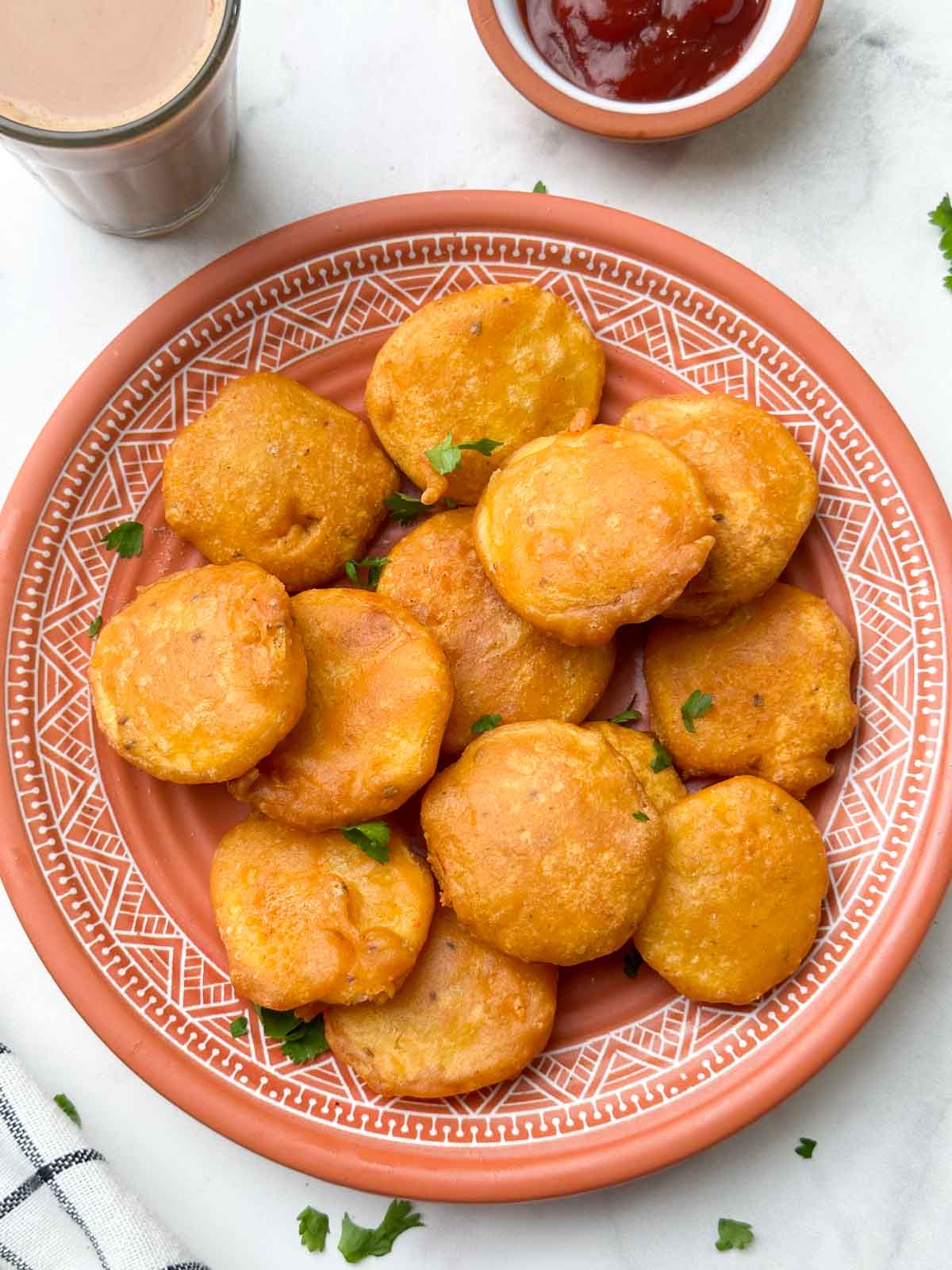 potato bajjis in a plate with tea and ketchup on the side