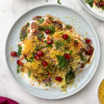 aloo tikki chaat serve don a plate with chutneys, sev and pomegranate seeds on the side