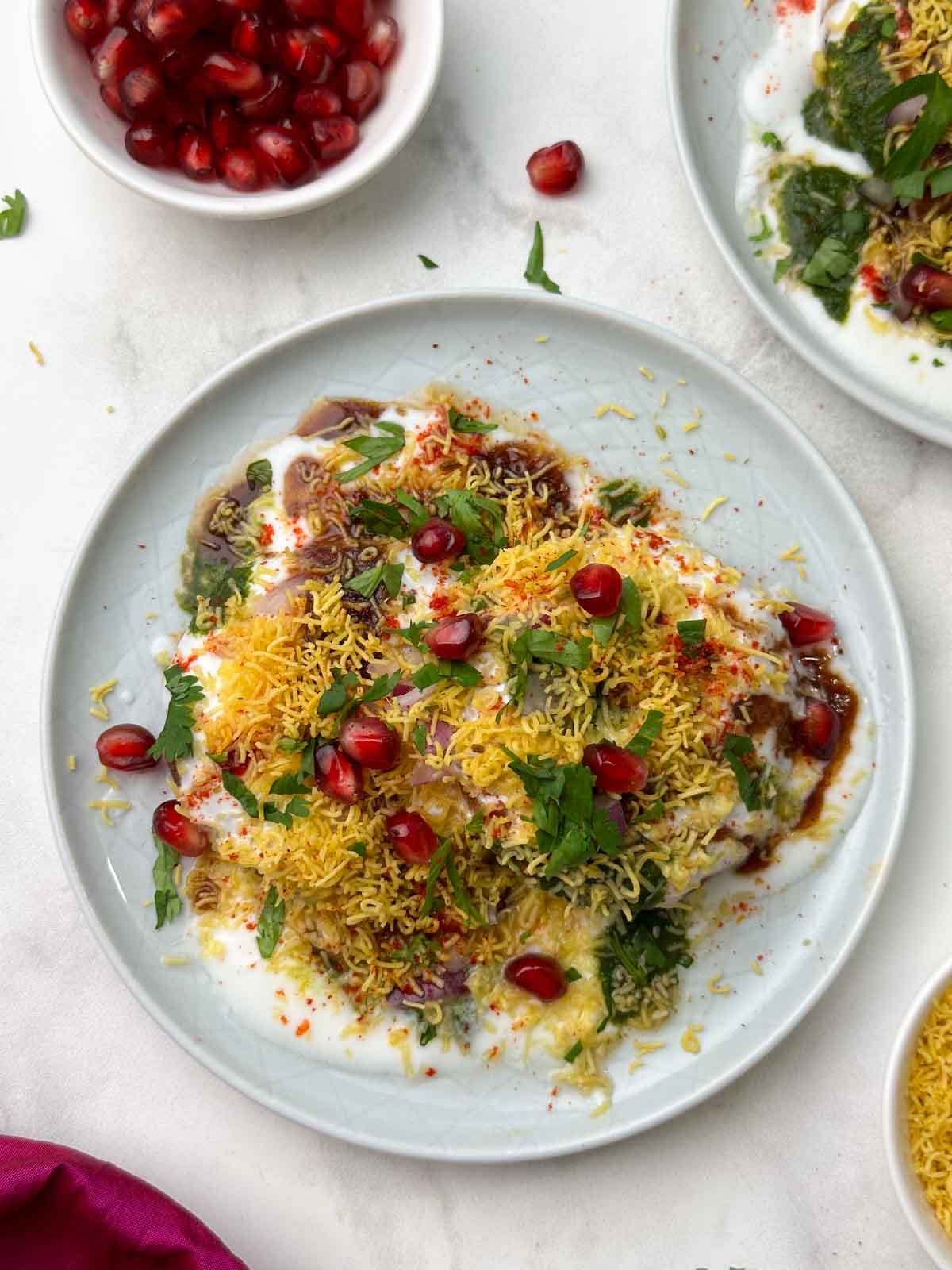 aloo tikki chaat serve don a plate with chutneys, sev and pomegranate seeds on the side