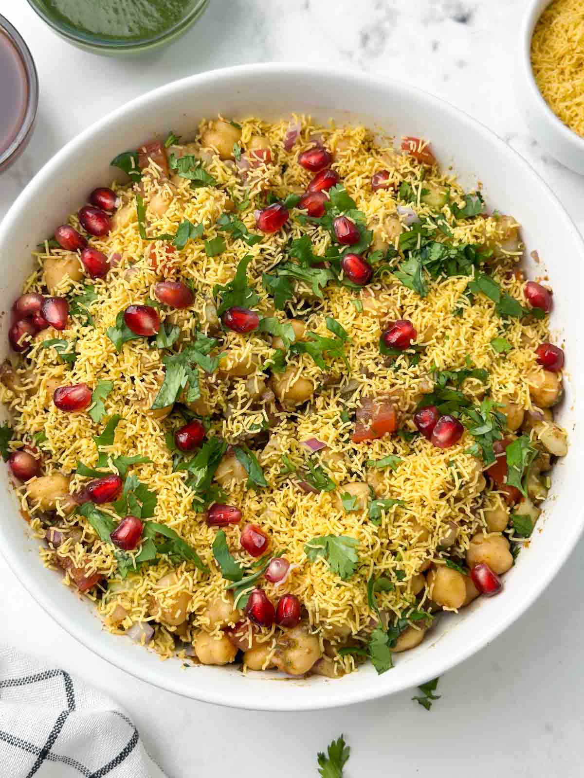 chana chaat served in a bowl and chutneys and sev on the side
