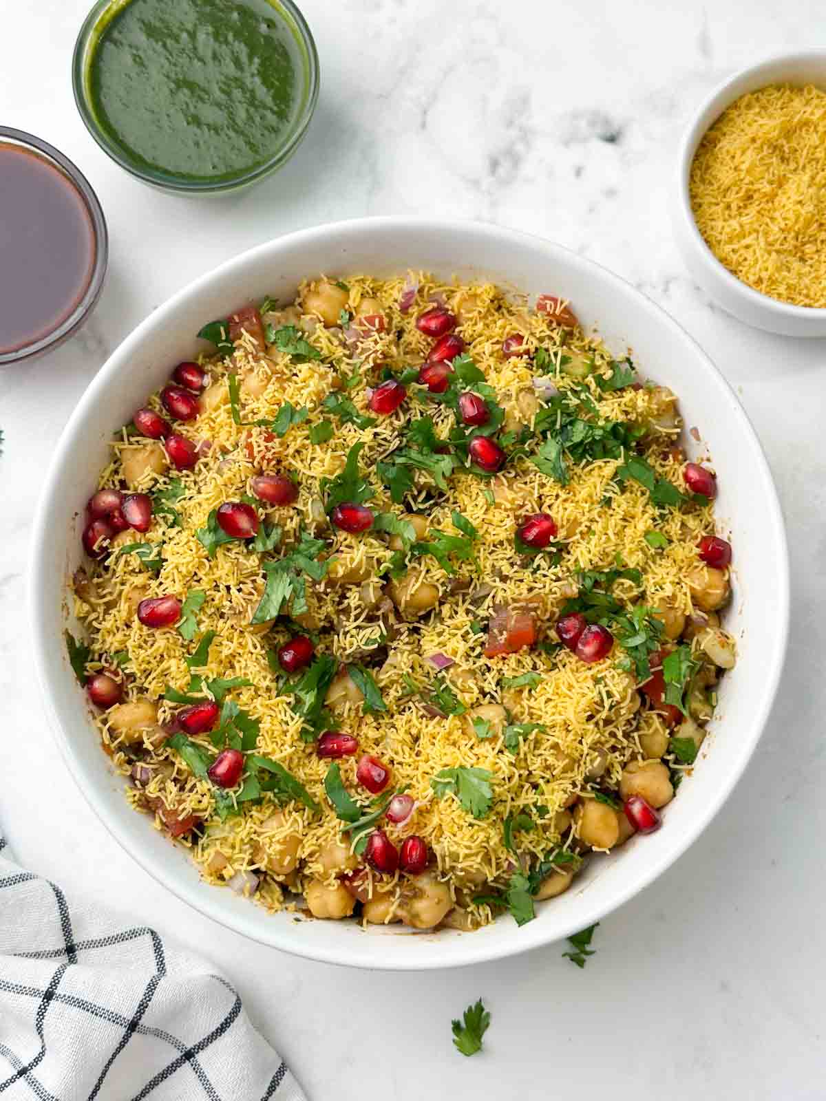 chickpea chaat served in a bowl and chutneys and sev on the side