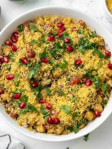 chana chaat served in a bowl and chutneys and sev on the side