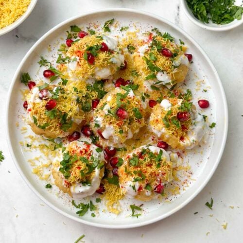 dahi puri chaat served on a plate with sev, coriander and pomegranate on the side