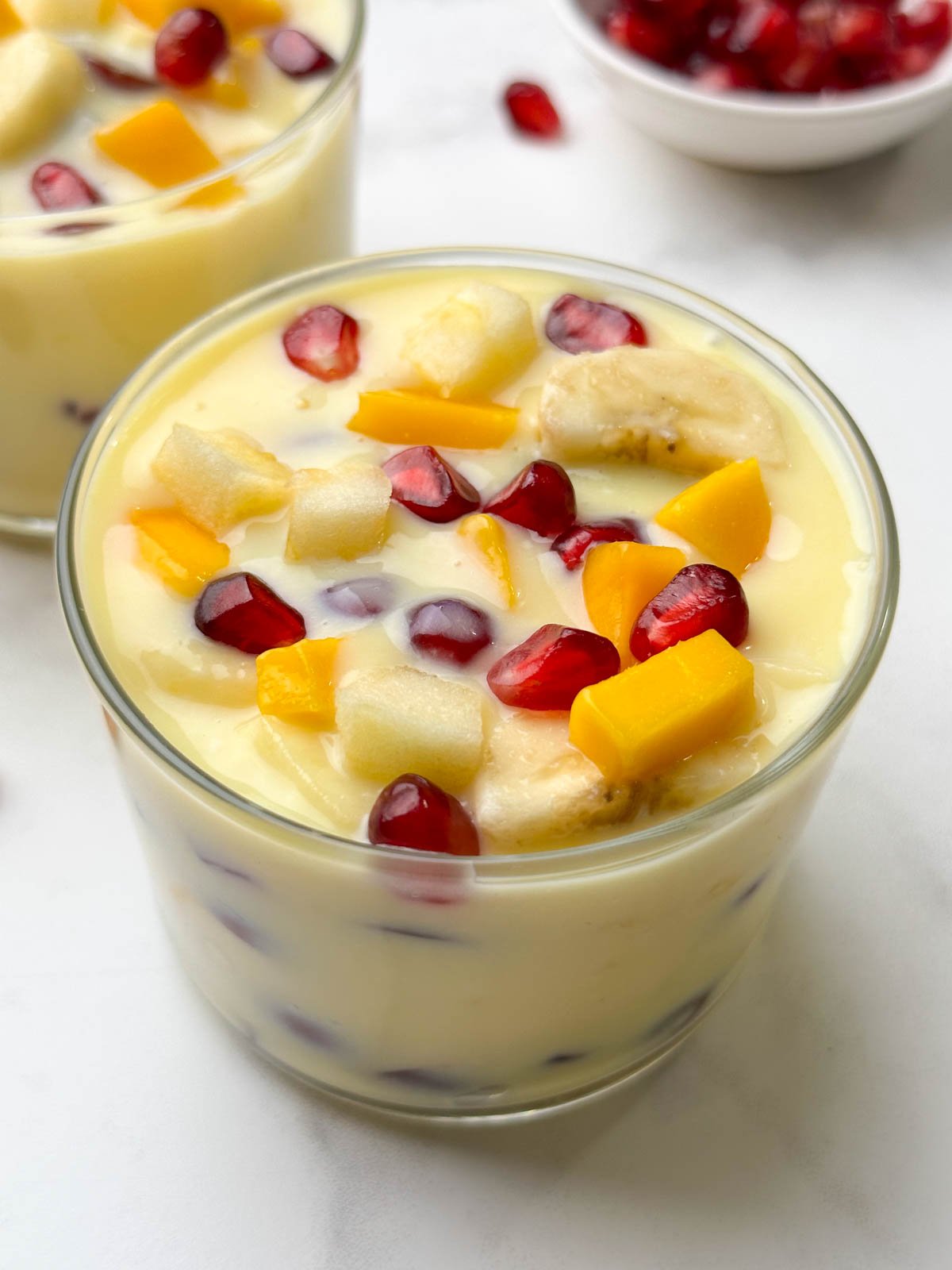 fruit custard served in 2 glass bowls with a spoon