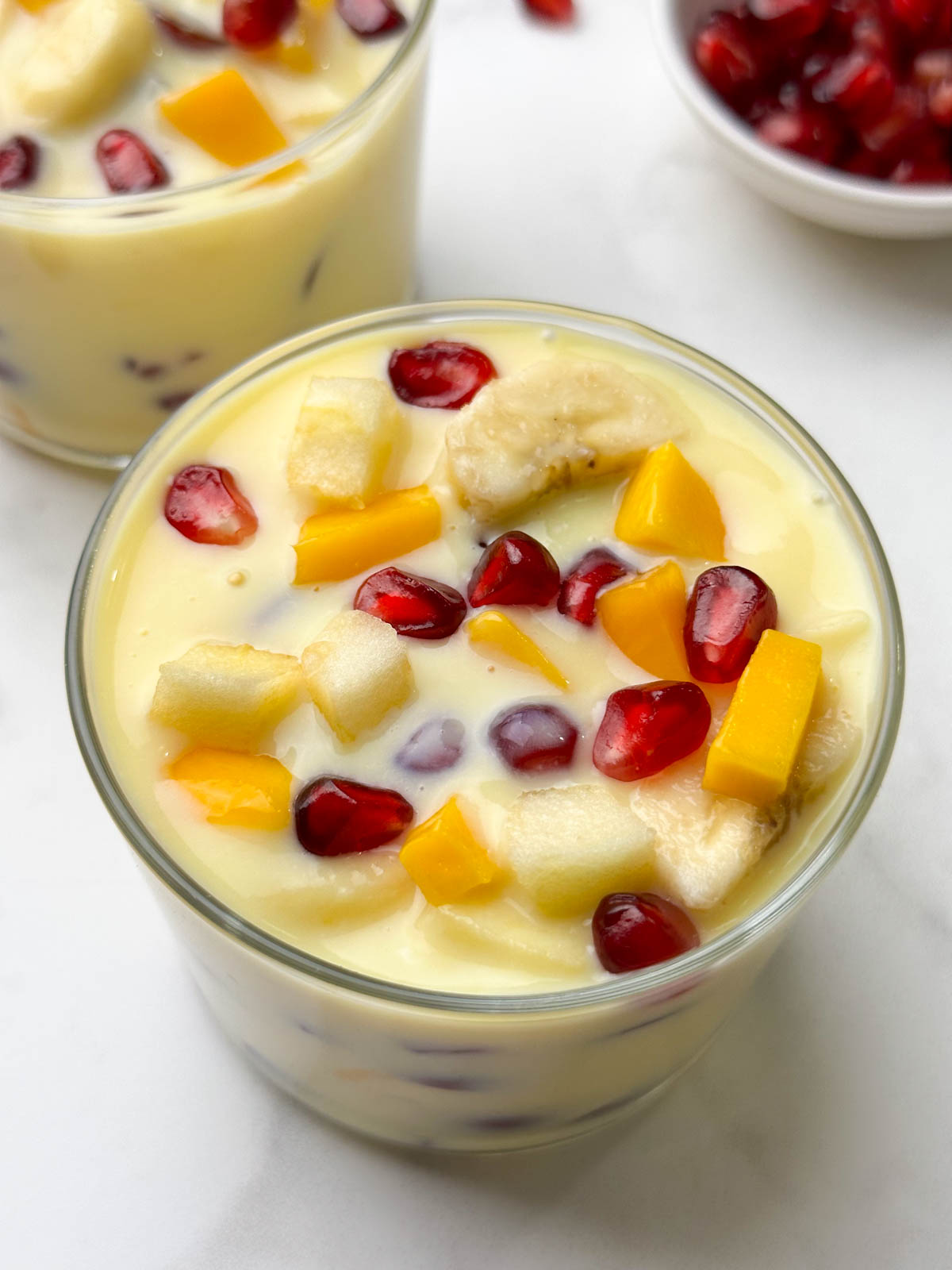 fruit custard served in 2 glass bowls with a spoon