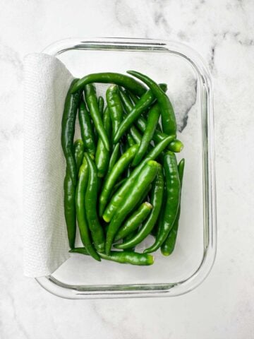 chili peppers on a glass container lined with paper towel