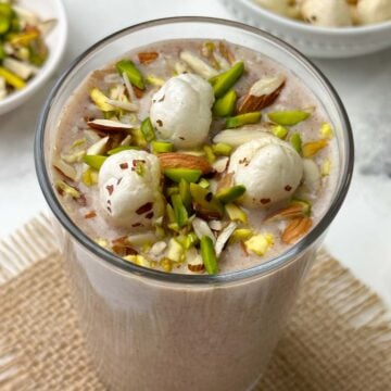 ragi makhana smoothie served in a glass topped with roasted makhana and nuts