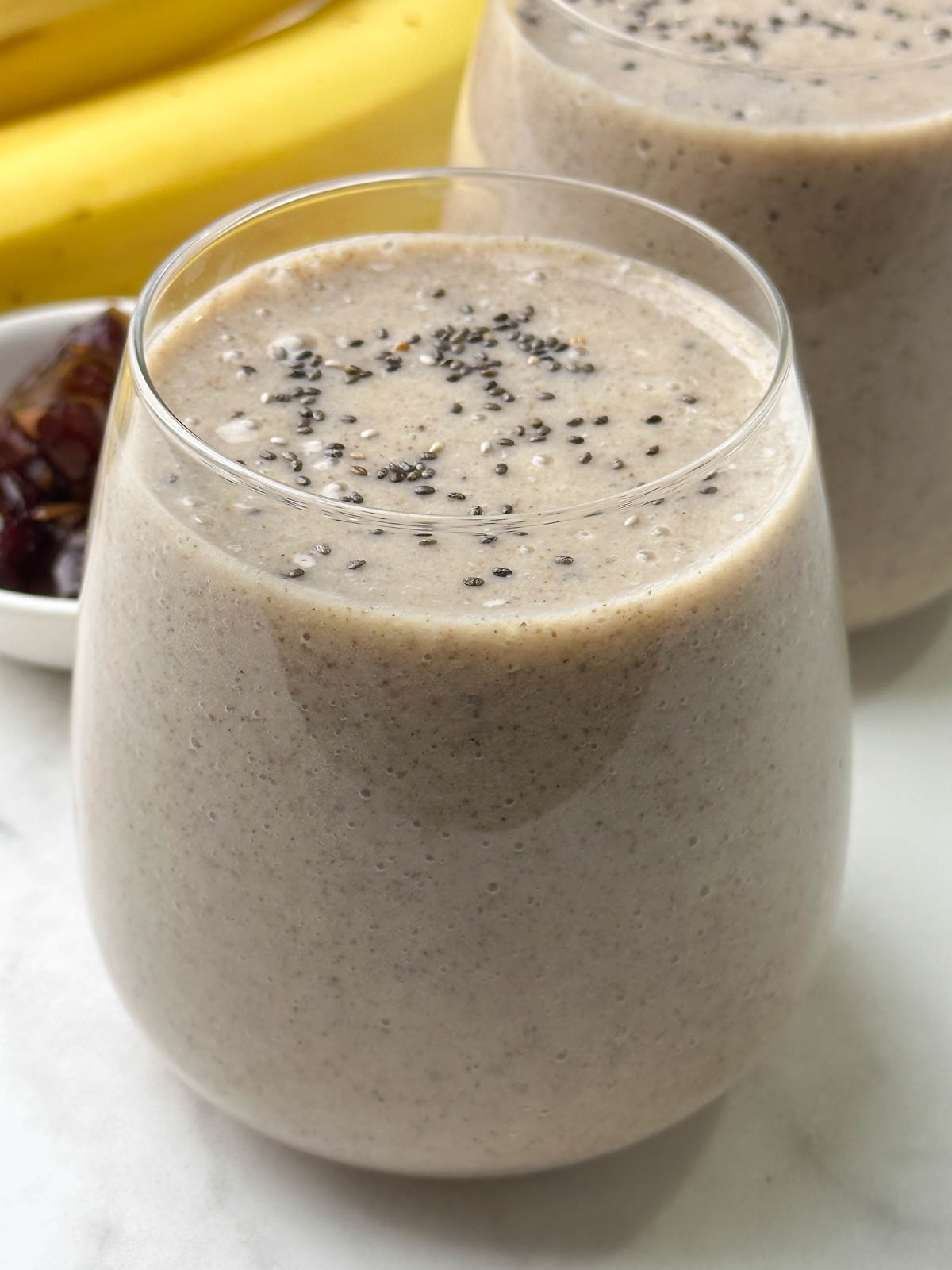 banana date smoothie served in 2 glasses topped with chia seeds