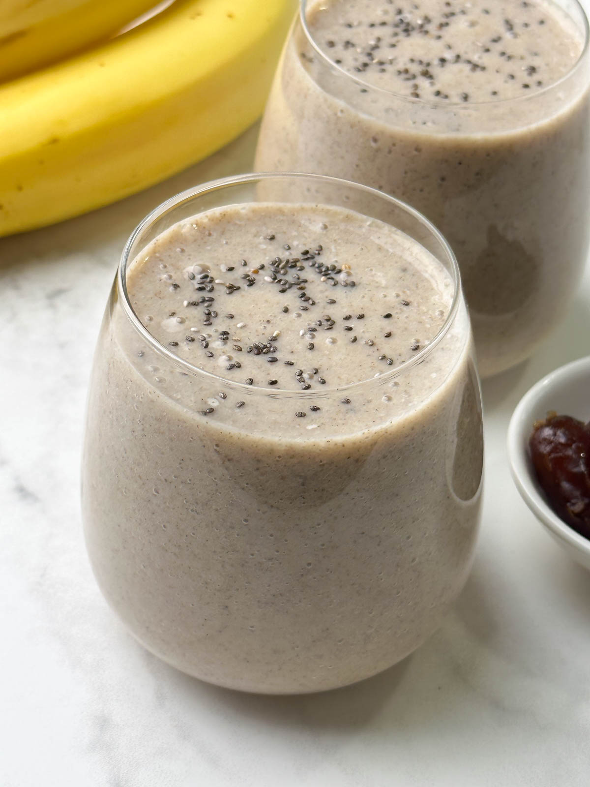 two glases of date banana smoothie served with chia seeds on the top