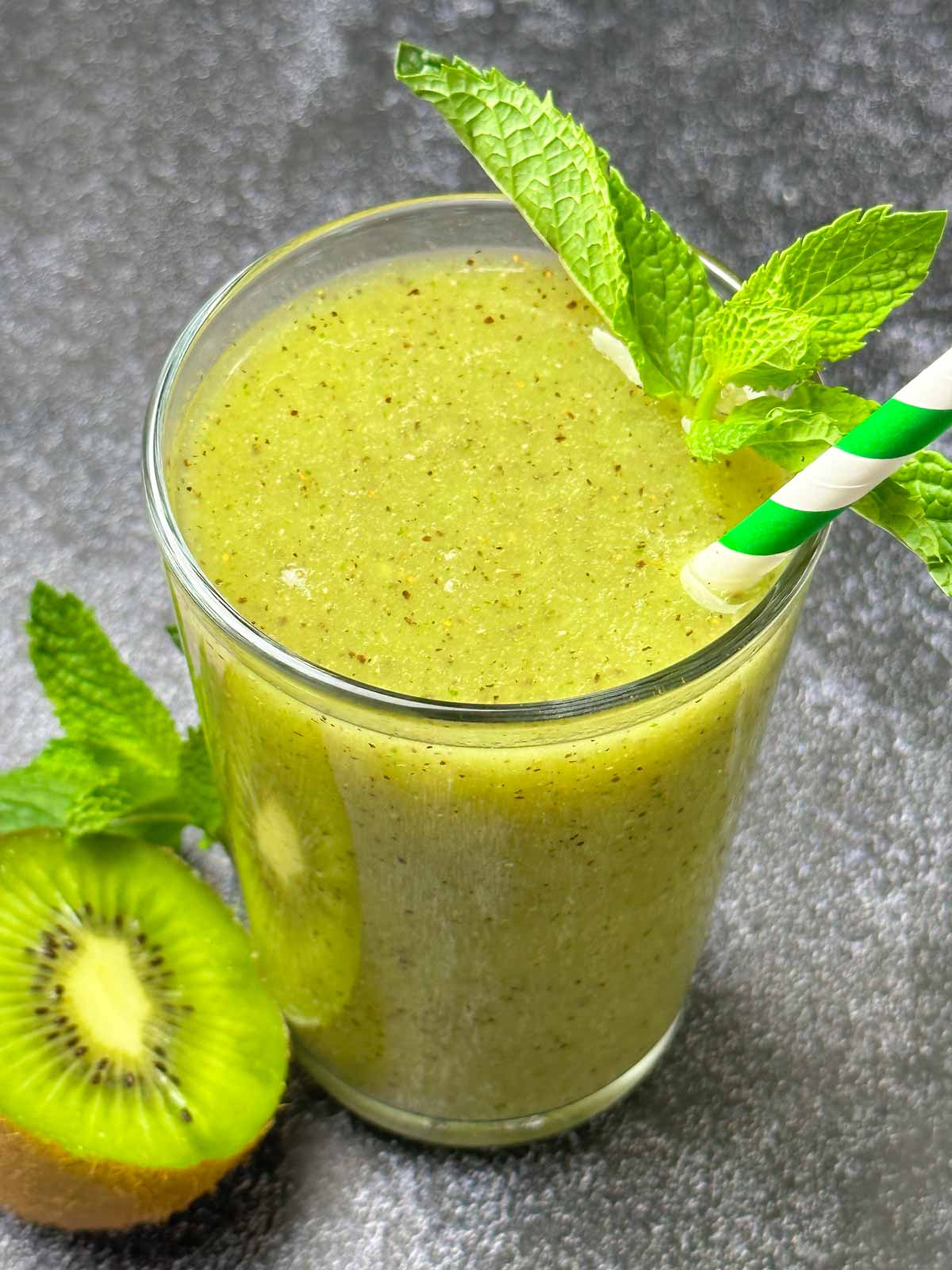 kiwi juice served in a glass garnished with mint and ½ kiwi ont he side