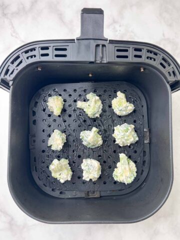 coated broccoli in the air fryer basket