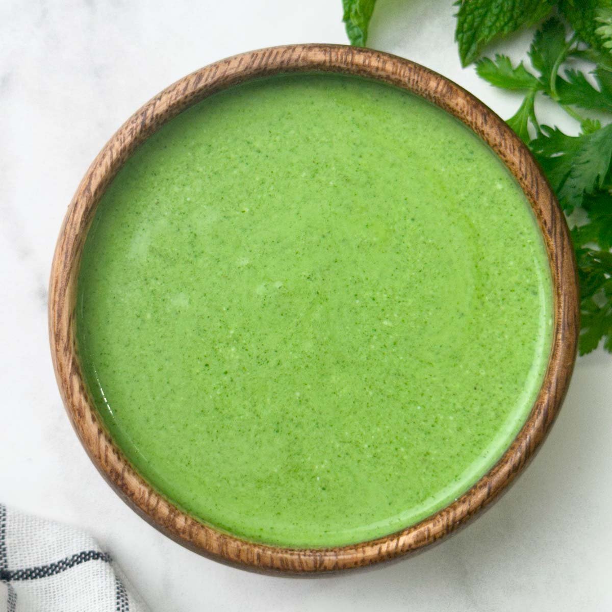 Mint yogurt chutney served in a bowl with herbs on the side