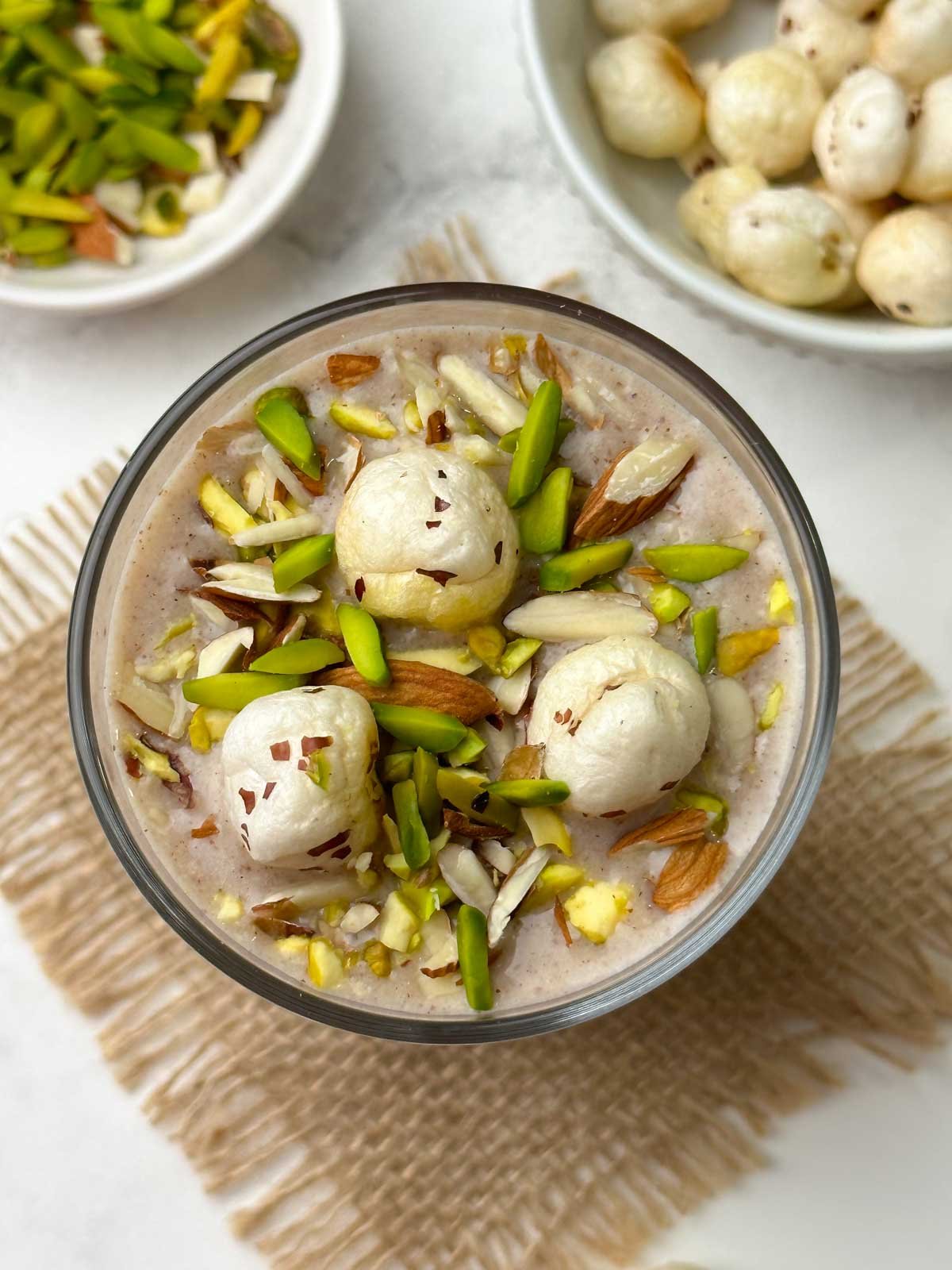 ragi makhana smoothie served in a glass topped with roasted makhana and nuts