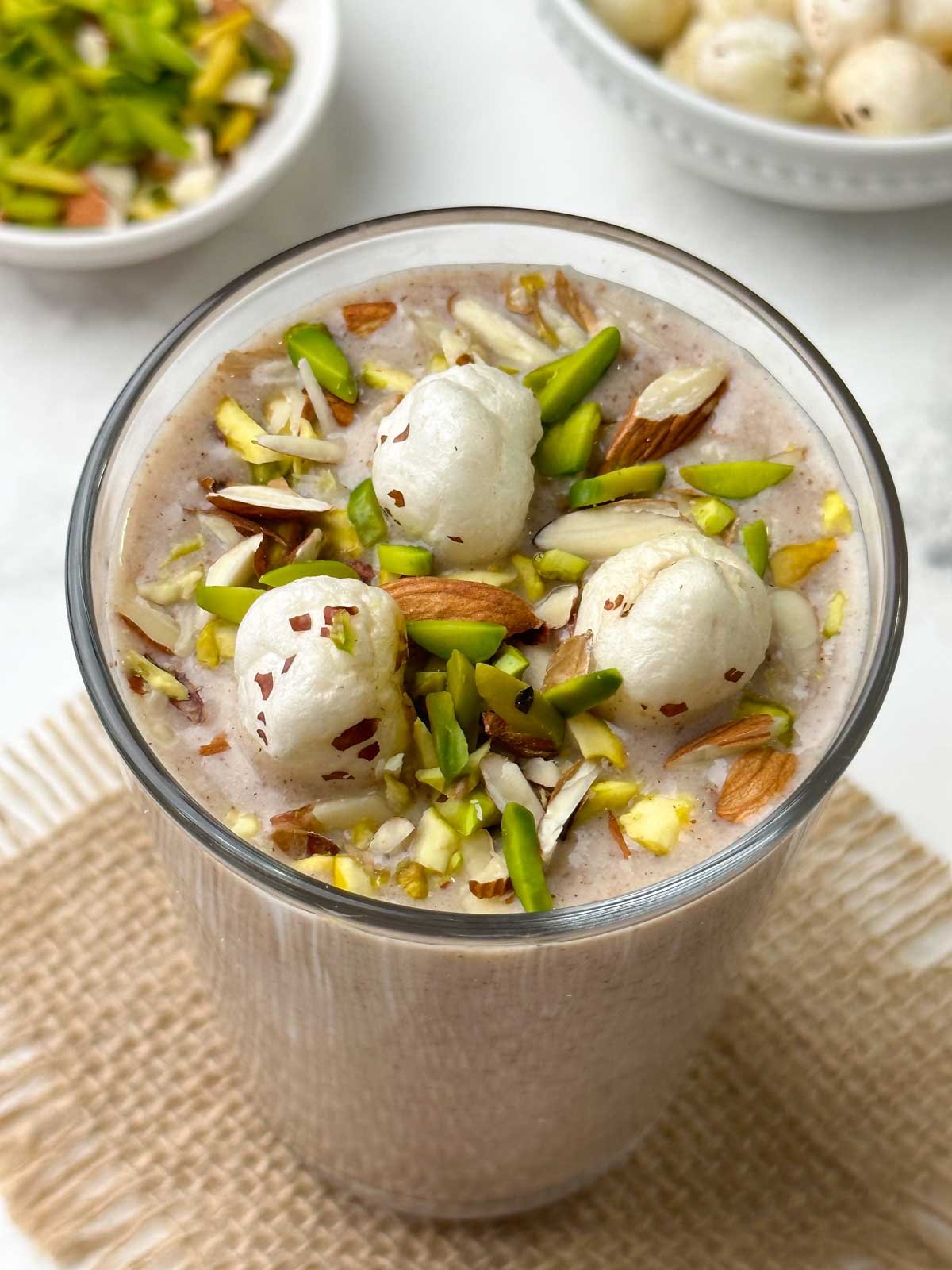 ragi makhana smoothie served in a glass topped with roasted makhana and nuts