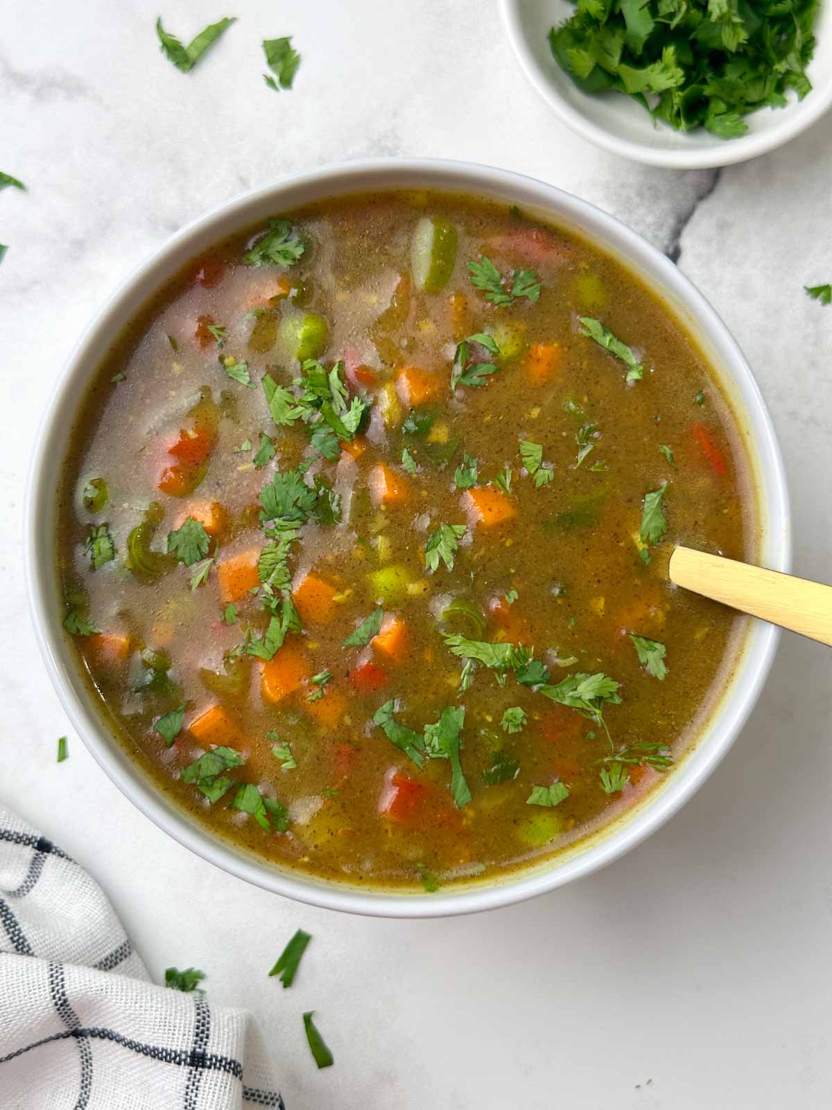 ragi vegetable soup served in a bowl with a spoon and cilantro on the side