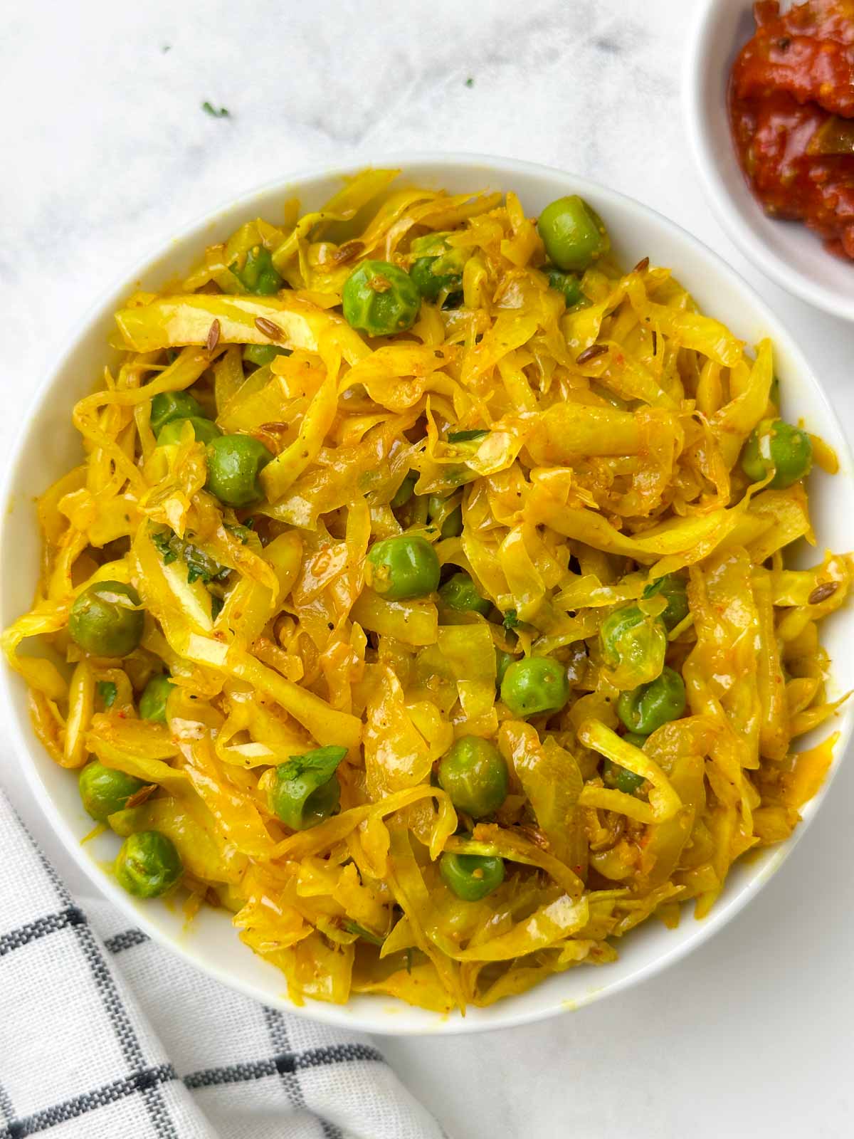 cabbage peas stir fry served in a bowl with pickle on the side