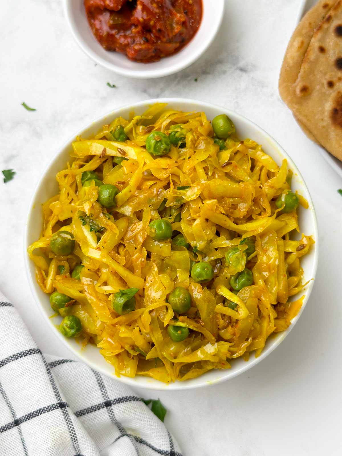 cabbage peas stir fry served in a bowl with paratha and pickle on the side