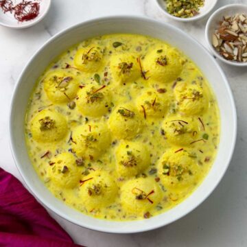 Easy rasmalai in a serving bowl garnished with nuts and saffron