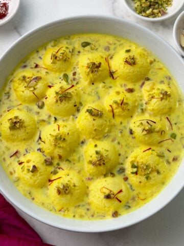 Easy rasmalai in a serving bowl garnished with nuts and saffron