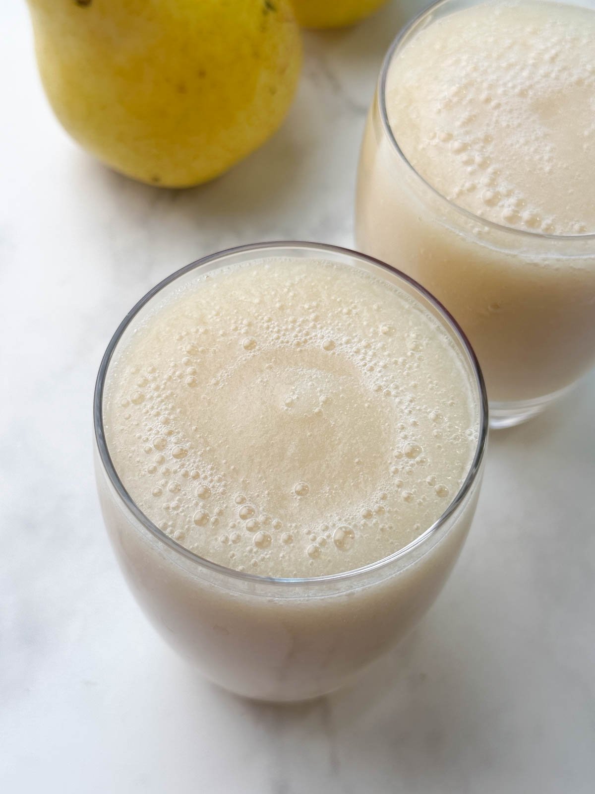 pear juice served in 2 glasses with pear on the side