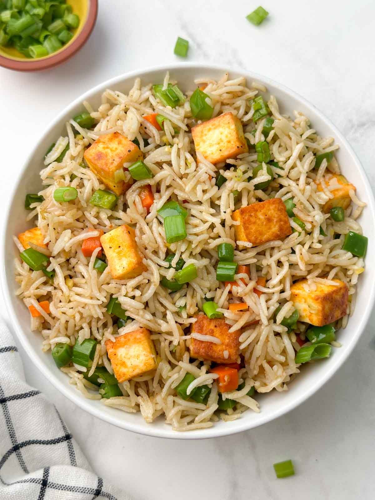 paneer vegetable fried rice in a bowl with green onions on the side