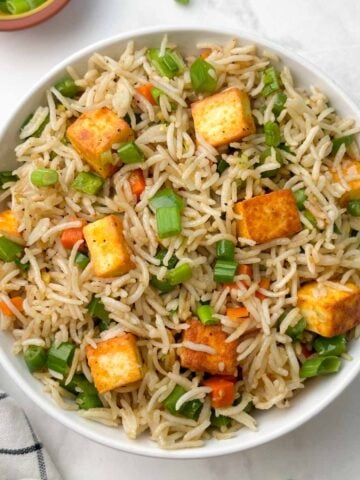 paneer vegetable fried rice in a bowl with green onions on the side