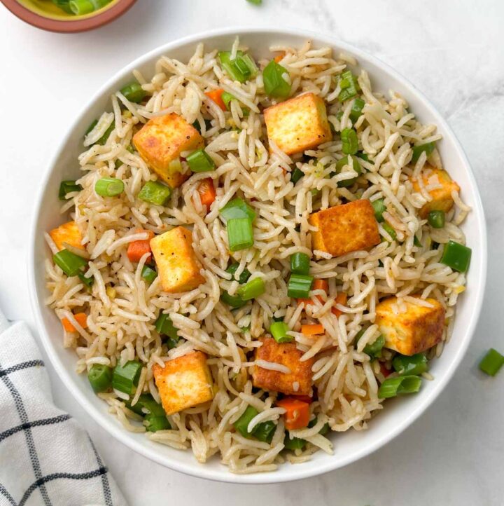 paneer vegetable fried rice in a bowl with green onions on the side