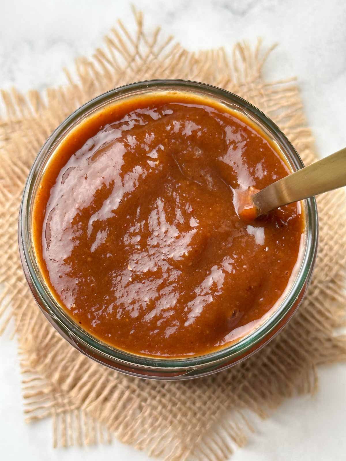 tamarind chutney in a glass jar with a spoon