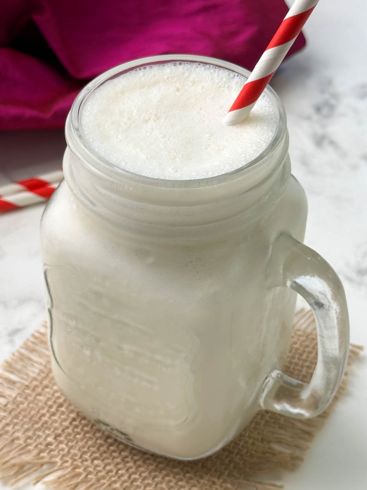 homemade classic vanilla milkshake in a serving glass with a straw