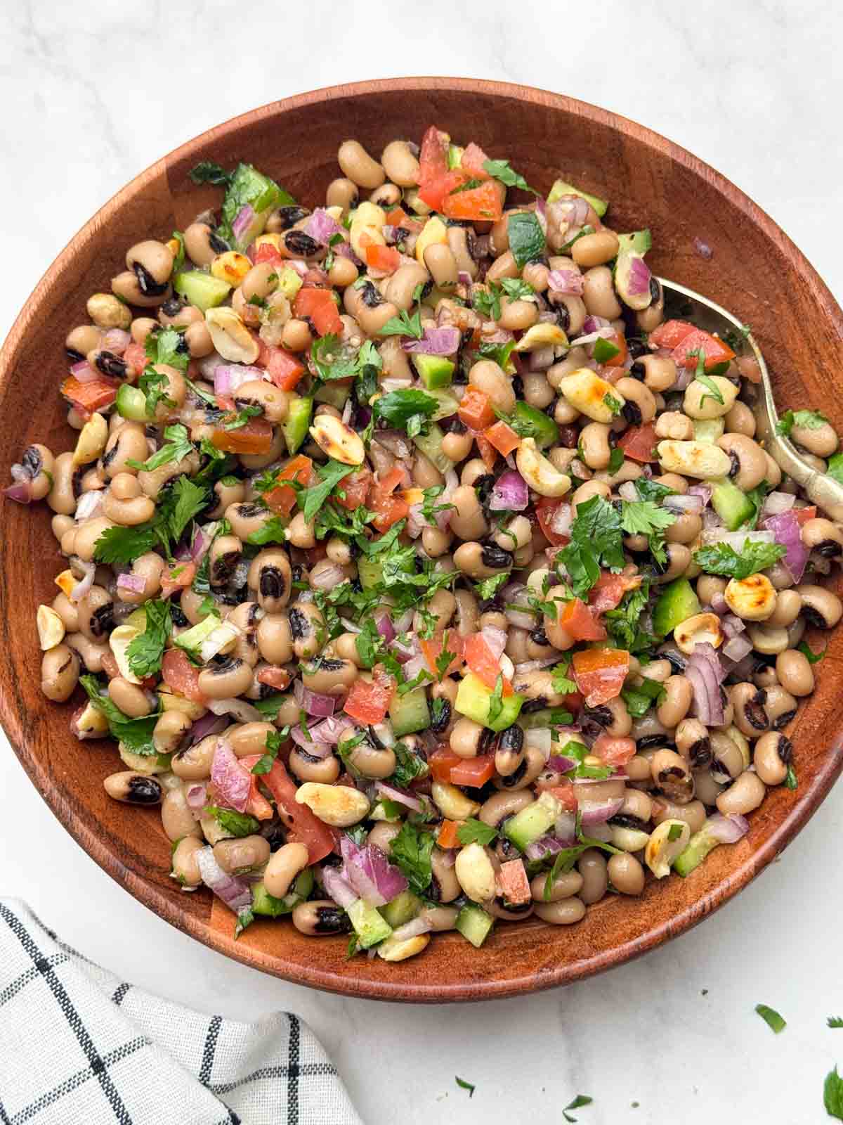 black eyed peas salad (lobia chaat) served in a wooden bowl with a spoon.