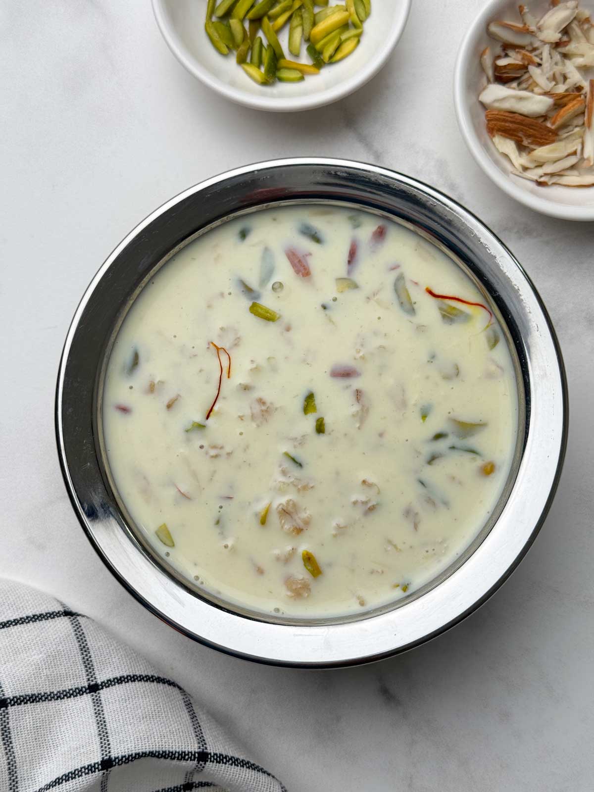 rolled oats kheer served in a bowl with nuts on the side