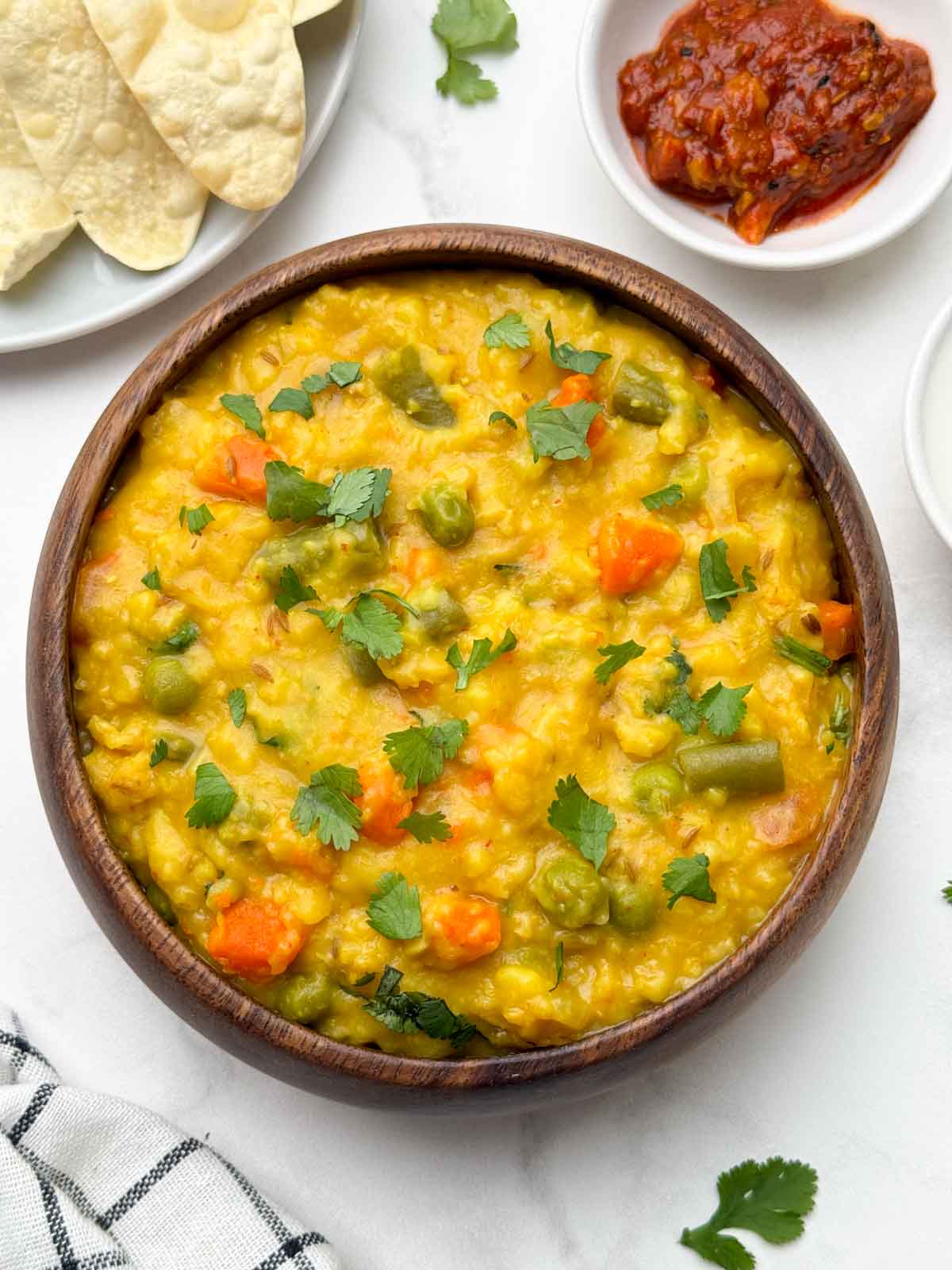 vegetable oats khichdi served in a bowl with papd and pickle on the side