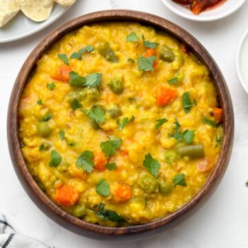 vegetable oats khichdi served in a bowl with papd and pickle on the side