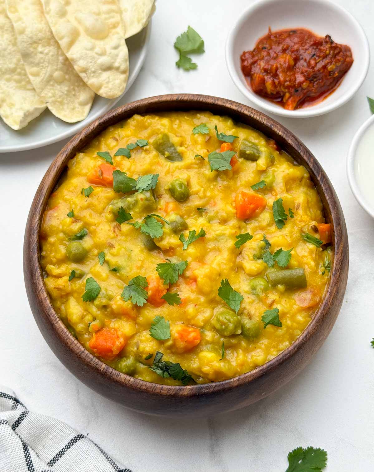 vegetable oats khichdi served in a bowl with papd and pickle on the side