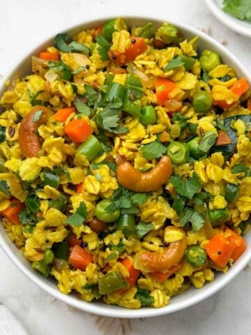 vegetable oats upma served in a bowl with coriander leaves on the side