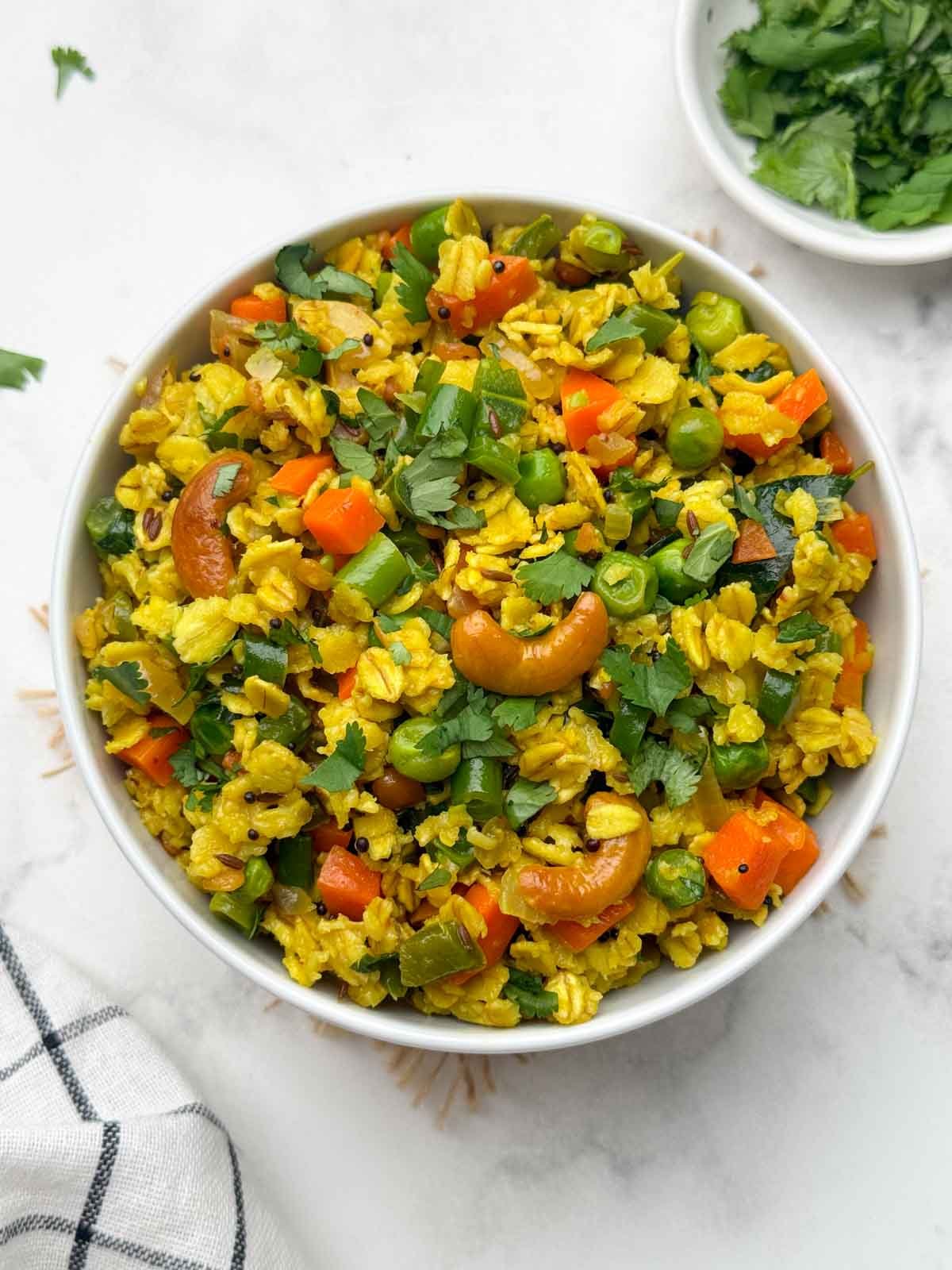 vegetable oats upma served in a bowl with coriander leaves on the side