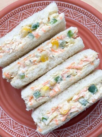 four slices of vegetable cream cheese sandwich in a plate