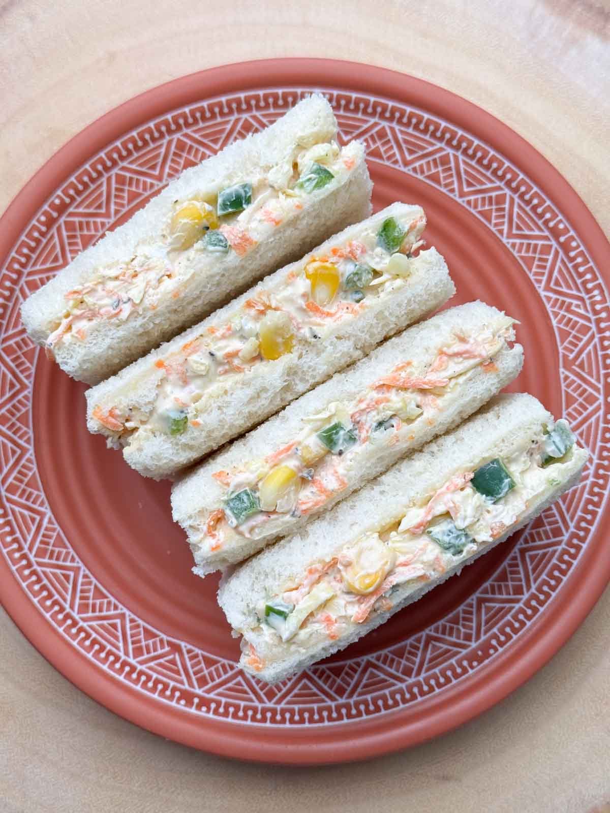 four slices of vegetable cream cheese sandwich in a plate